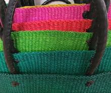 Load image into Gallery viewer, Close-up of a woven straw tote bag with vibrant horizontal stripes in pink, red, green, and teal, featuring dark brown twisted rope handles.
